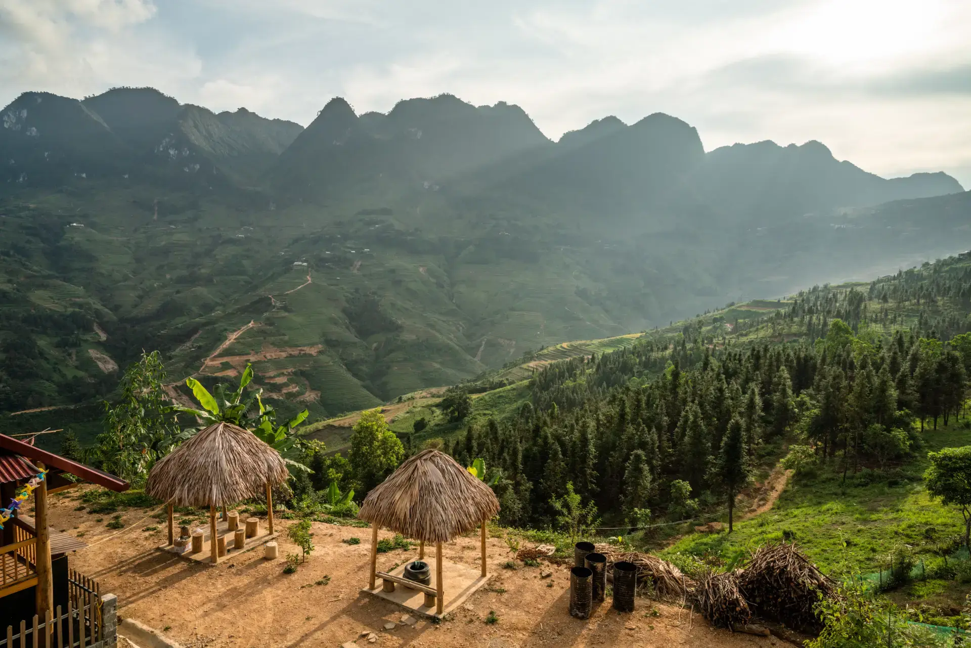Thatched nipa huts on a terraced hillside overlooking misty green mountains