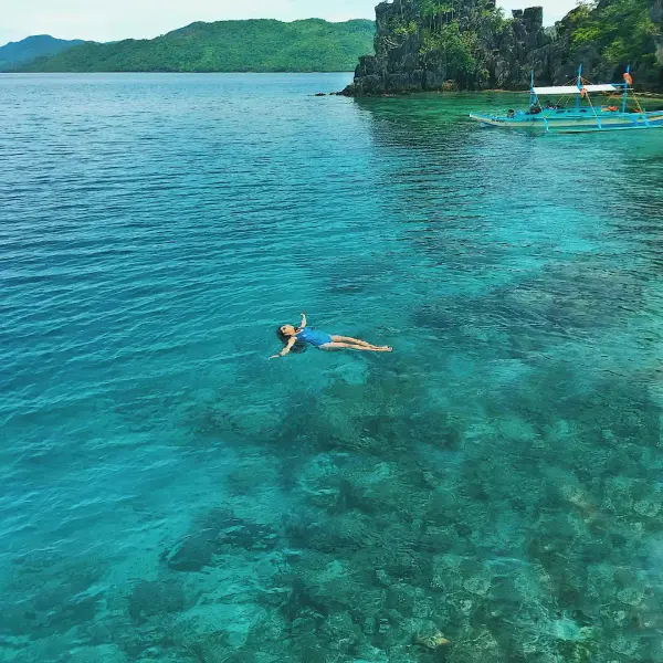 A swimmer floating in clear tropical water near a boat